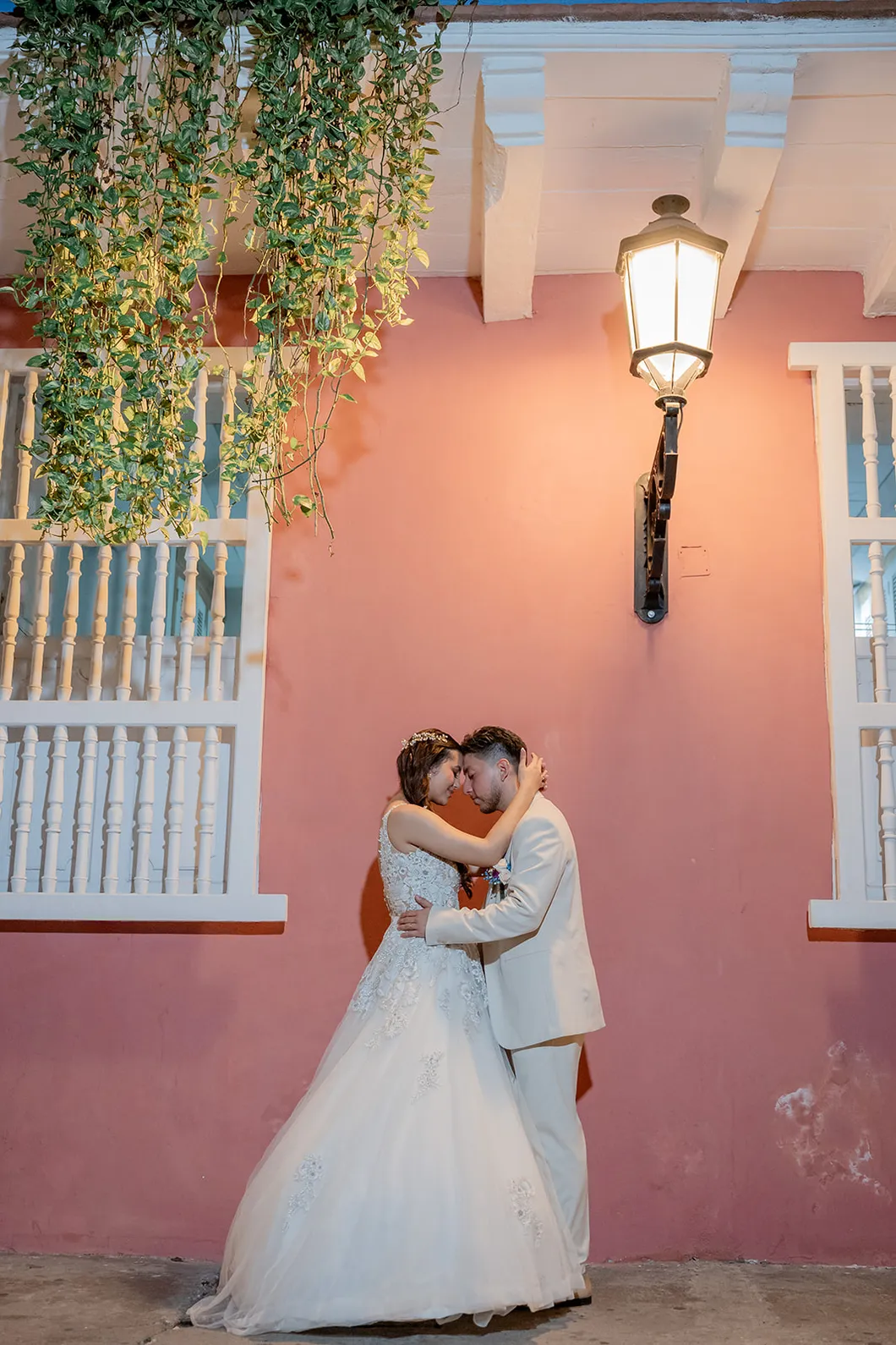 Novios abrazados frente a una fachada rosa de Cartagena, fotografiados por Omar Fraija
