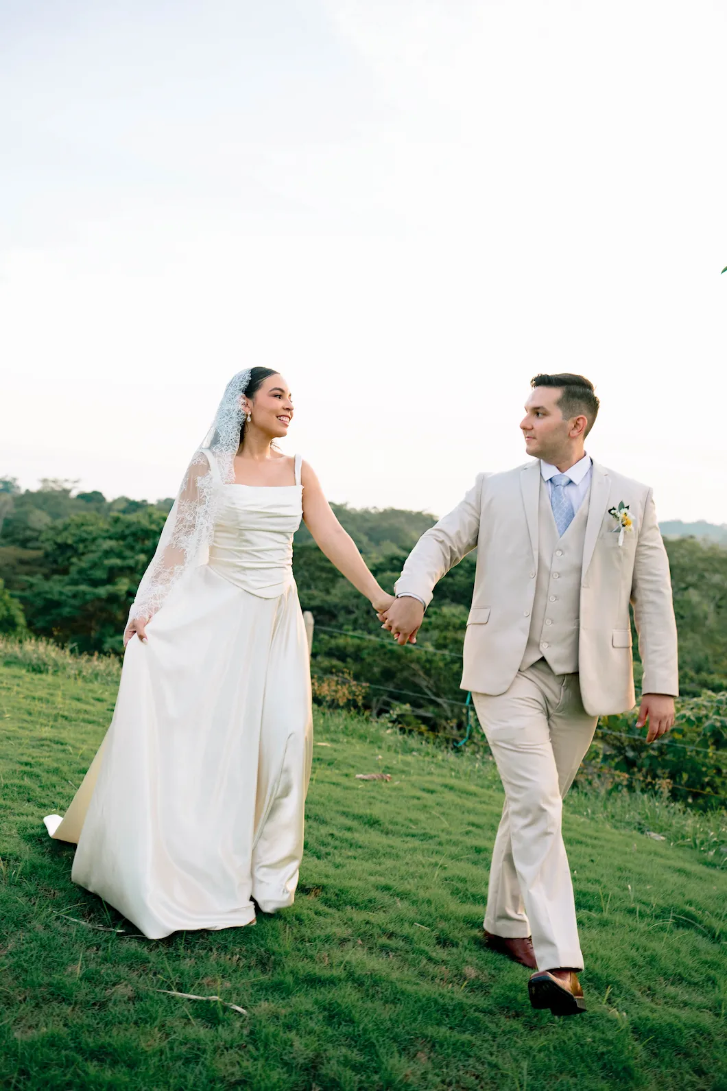 Los novios caminan de la mano por un prado al atardecer, por Omar Fraija
